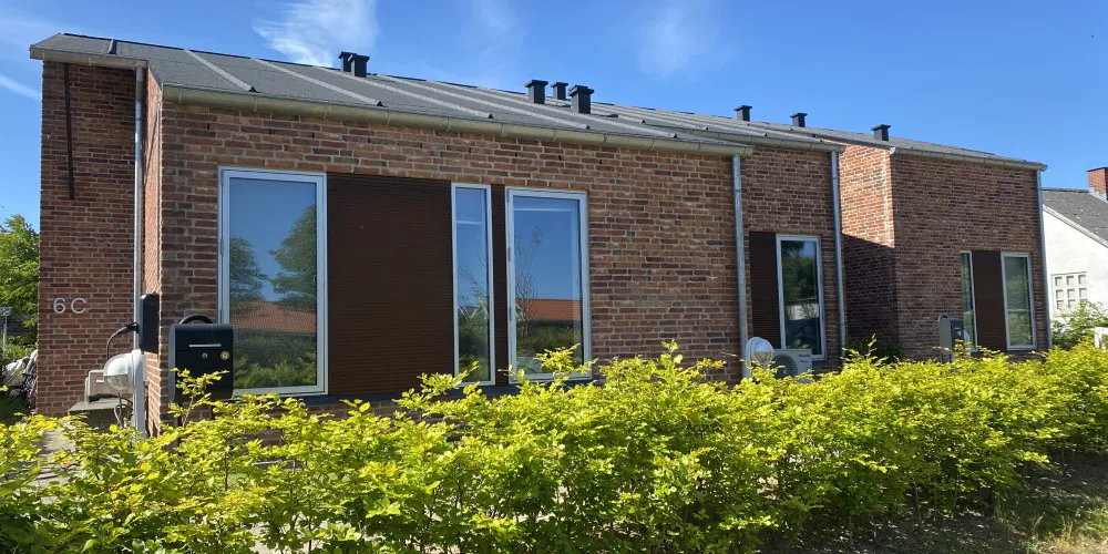 Rækkehus i røde mursten med grøn beplantning