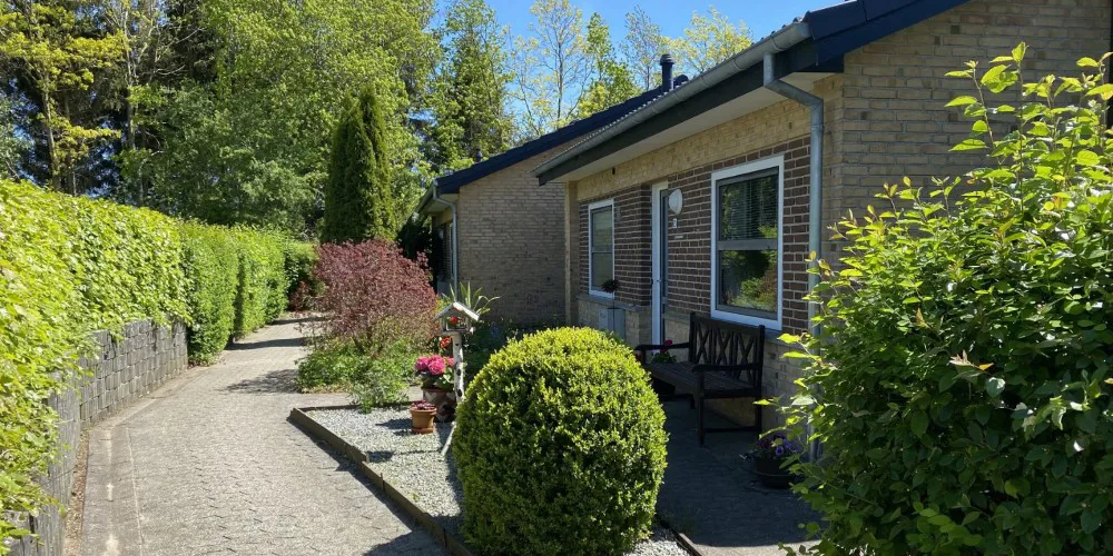 Rækkehuse opført i gule og brune mursten med grøn beplantning