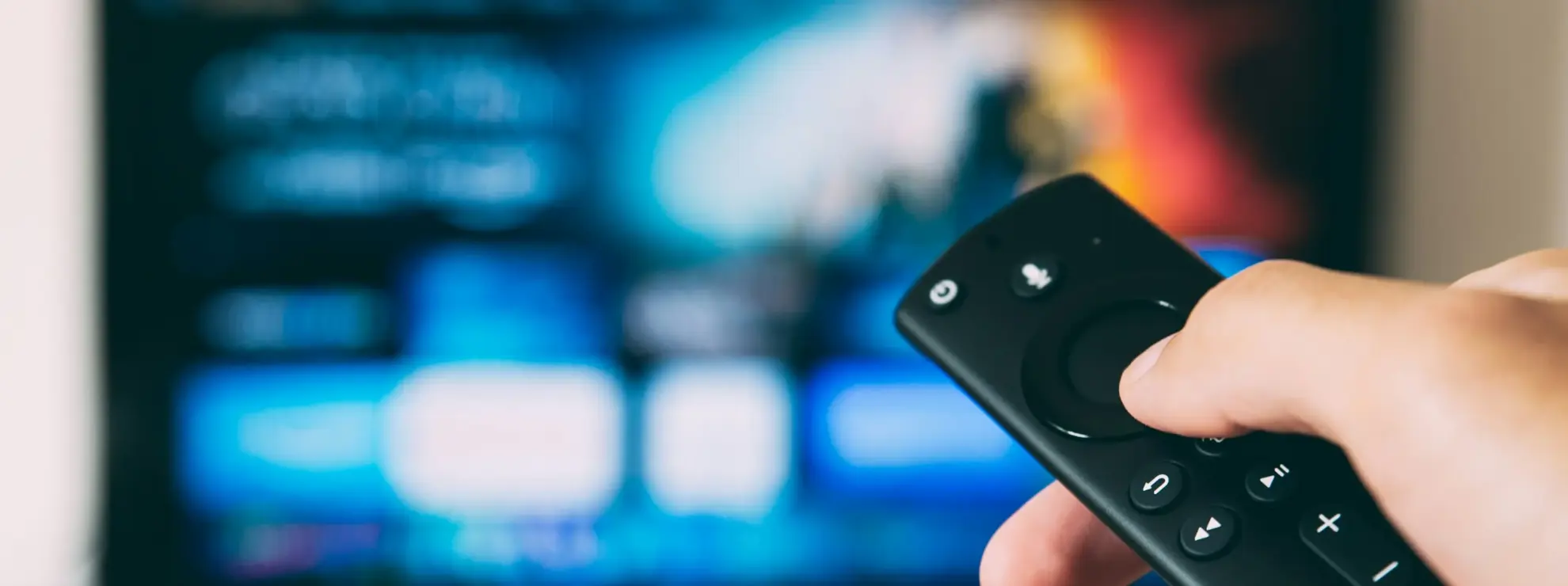 Menneske der holder en fjernbetjening foran et TV