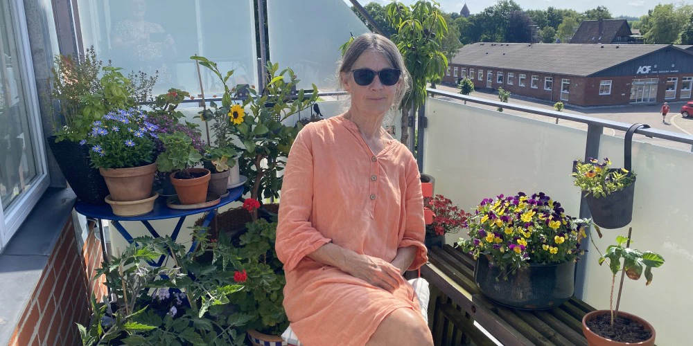 Hanne sidder på sin altan med farverige blomster